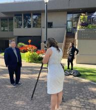 man in suit being interviewed by TV reporter. 